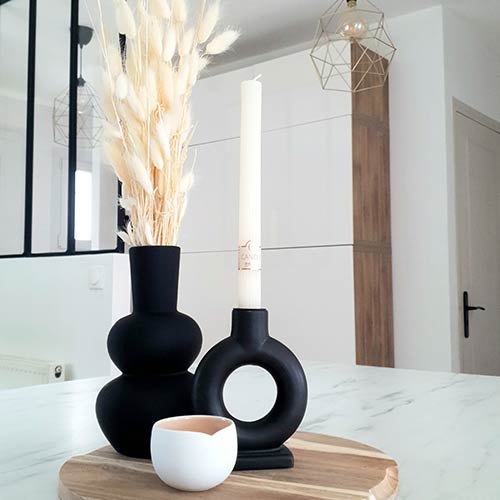 composition de trois objets décoratifs : une vase et deux bougeoirs noirs.